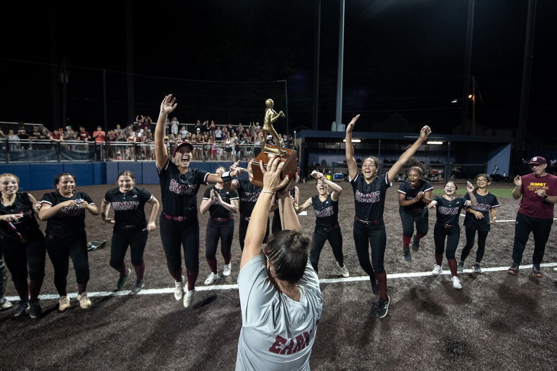 Summit Hilltoppers celebrating with the championship trophy under the lights