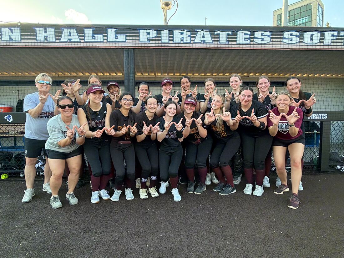 Team making a hand sign together in the dugout at Seton Hall